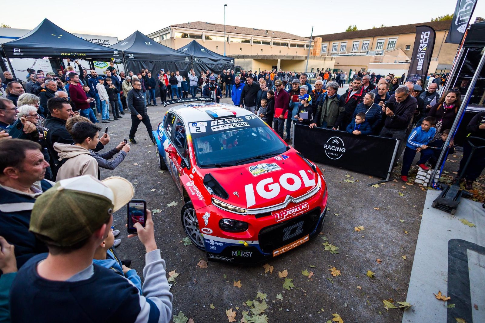Le public autour d’une voiture de rallye au parc fermé